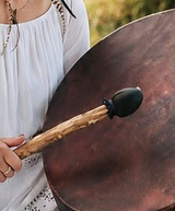 Une personne frappe un grand gong en bronze avec un maillet 