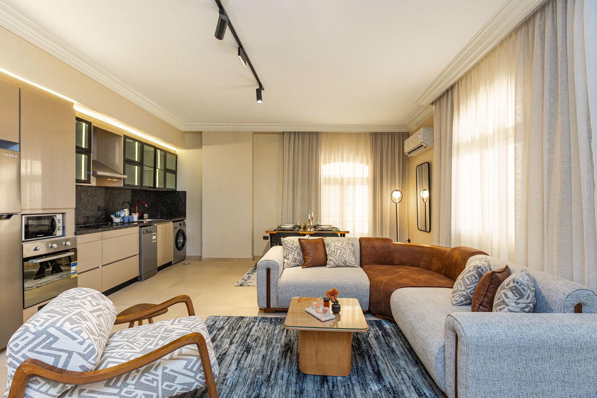 A living room with a couch , chair , coffee table and kitchen.