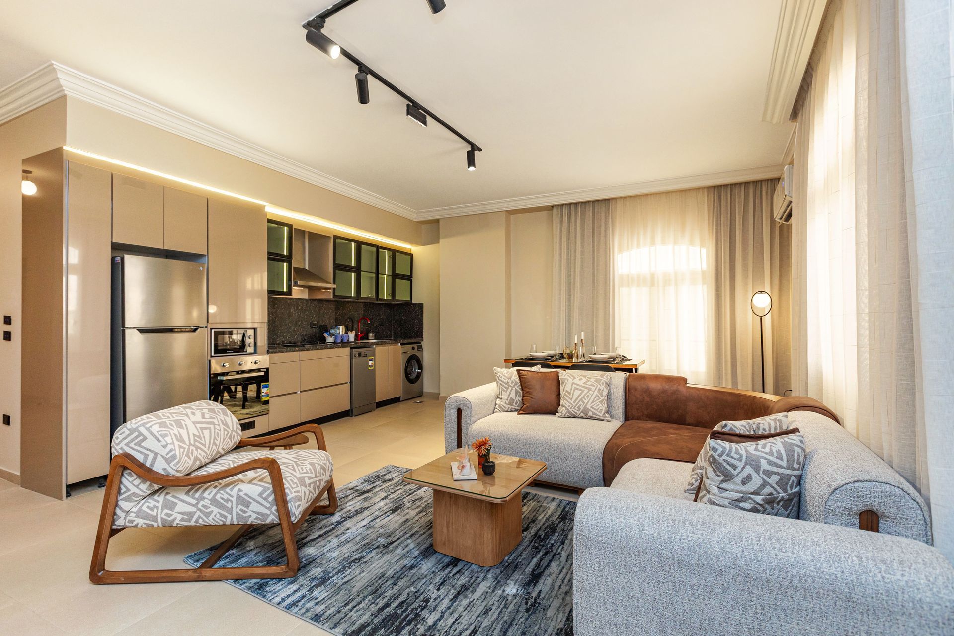 A living room with a couch , chair , coffee table and kitchen.