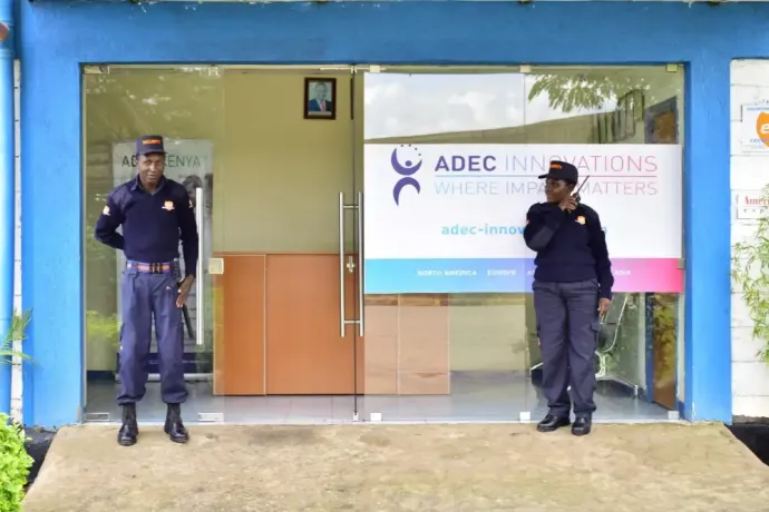 Two security guards are standing in front of a glass door.