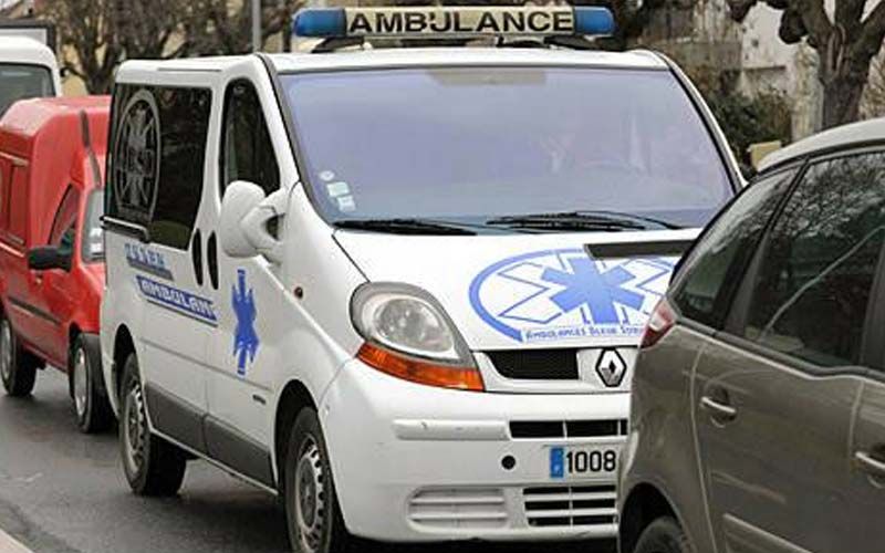 Ambulance blanche avec étoile bleue, stationnée dans la rue. Panneau « AMBULANCE » sur le toit.