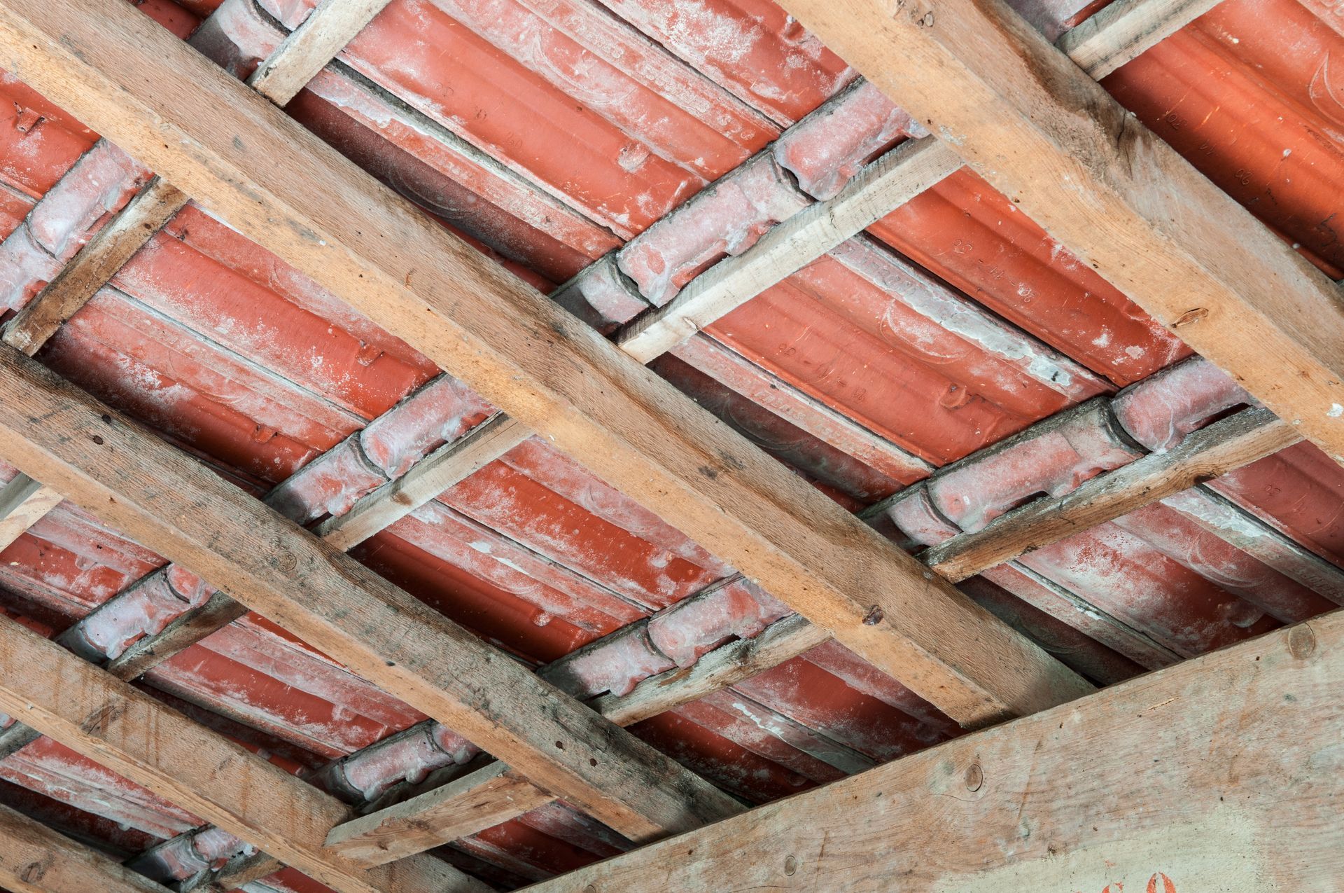 Vue d'en bas : chevrons en bois et tuiles rouges.