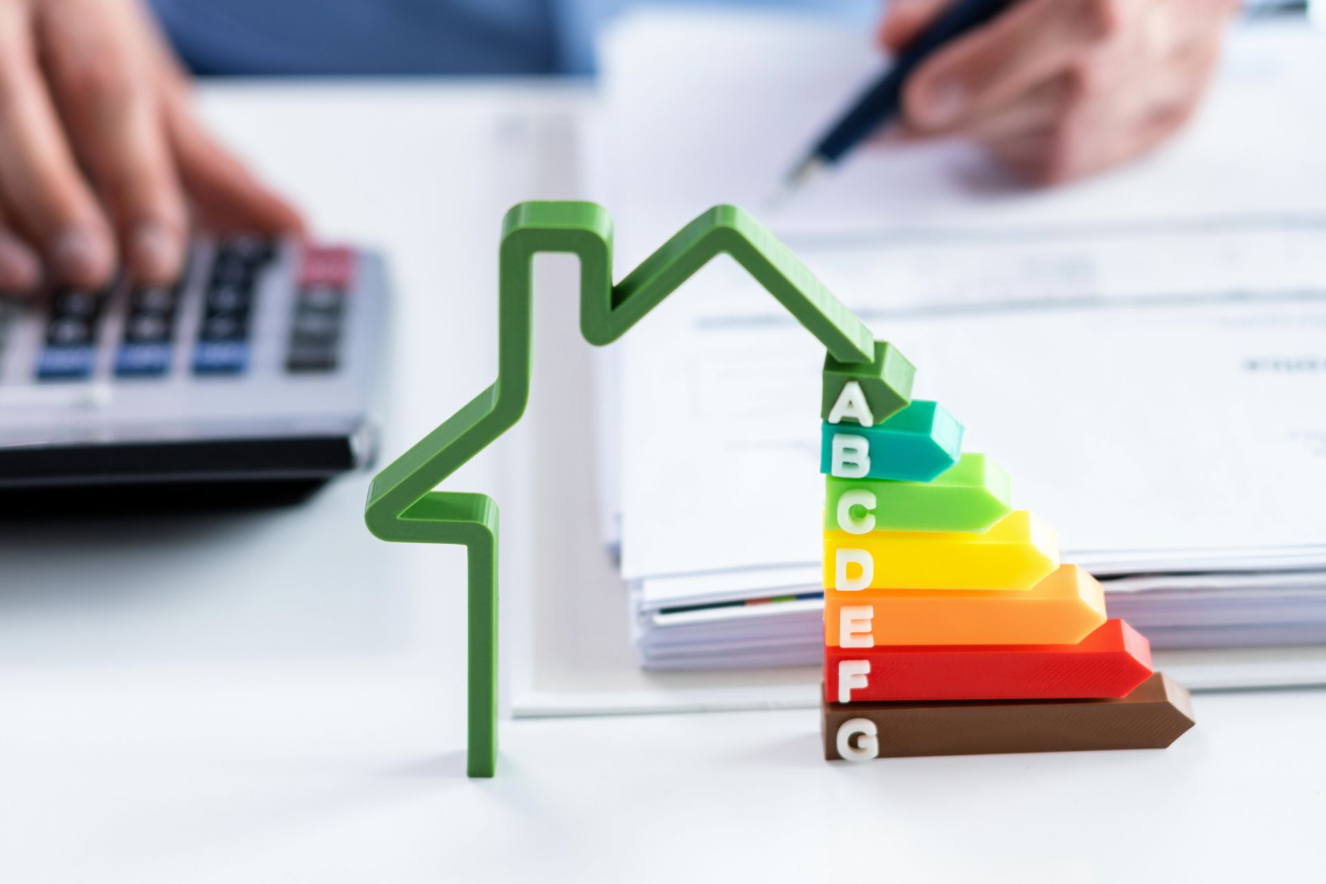 Personne en train de calculer, contour d'une maison verte avec indication de son efficacité énergétique.
