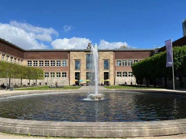 Ein großes Gebäude mit einem Brunnen davor.