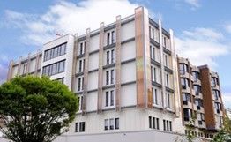 Ein großes Gebäude mit vielen Fenstern und einem Baum davor.