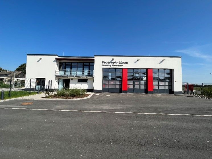 Ein großes weißes Gebäude mit roten Türen und einem Parkplatz davor.