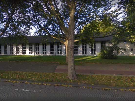 Ein weißes Gebäude mit einem Baum davor.