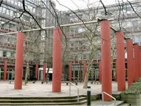 Eine Reihe roter Säulen in einem Hof ​​vor einem Gebäude.