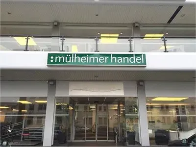 Ein weißes Gebäude mit einem grünen Schild mit der Aufschrift „Mülheimer Handel“.