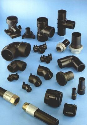 Un montón de accesorios de tubería de plástico negro sobre una superficie azul