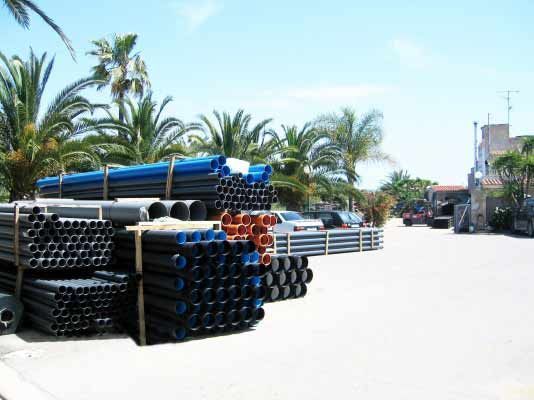 Un montón de tuberías están apiladas una encima de otra en un estacionamiento.
