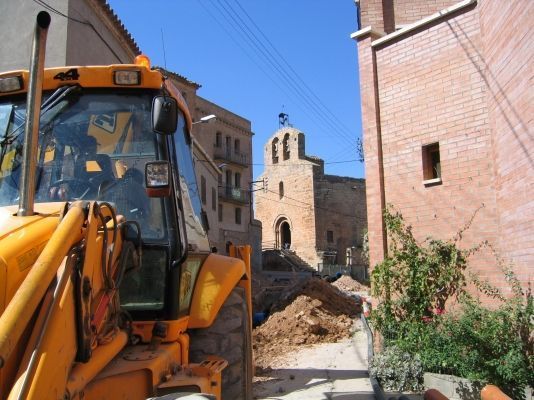 Un tractor amarillo está estacionado frente a un edificio de ladrillos.