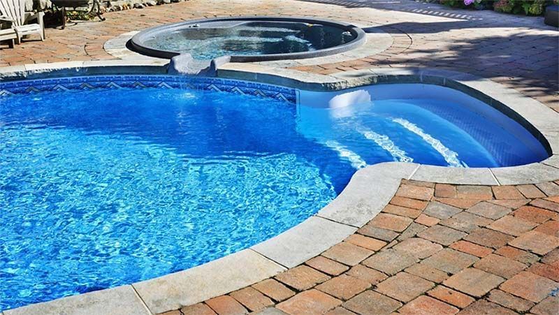 Una gran piscina con un jacuzzi al fondo.