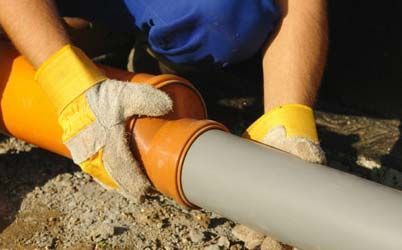 Un hombre que lleva guantes amarillos está trabajando en una tubería.