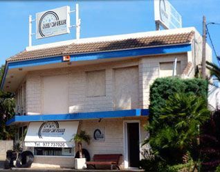 Un edificio blanco con techo azul y un cartel que dice 'neumáticos'.