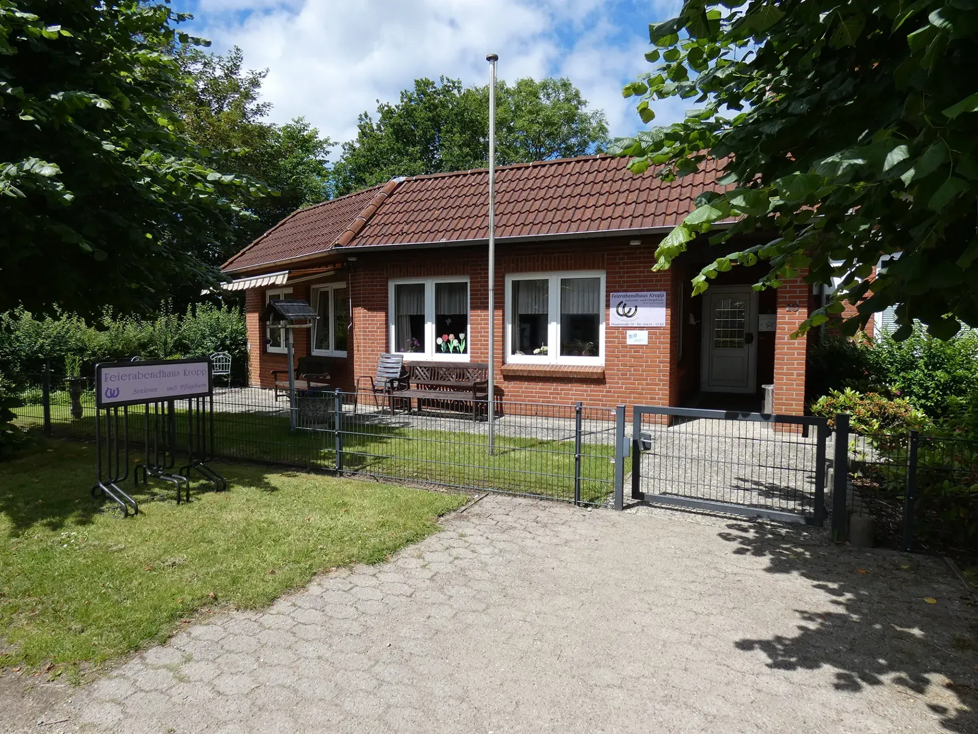 Ein kleines Backsteinhaus mit einem Zaun darum