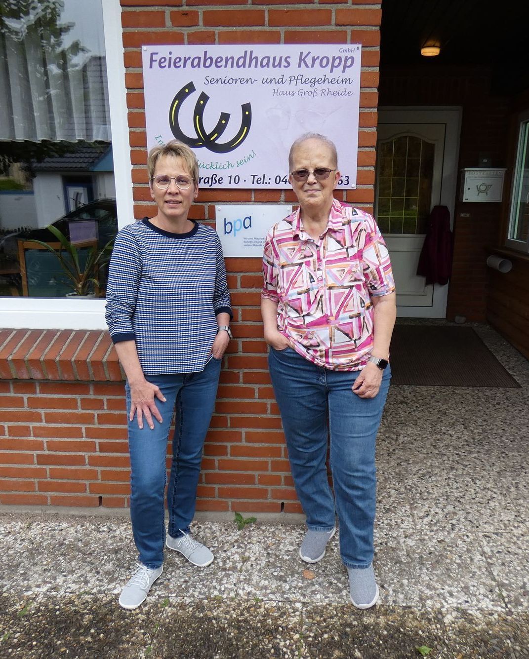 Zwei Frauen stehen vor einem Backsteingebäude.