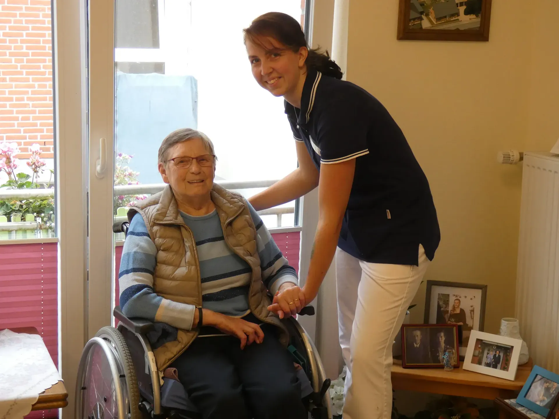 Eine Frau hilft einer älteren Frau im Rollstuhl