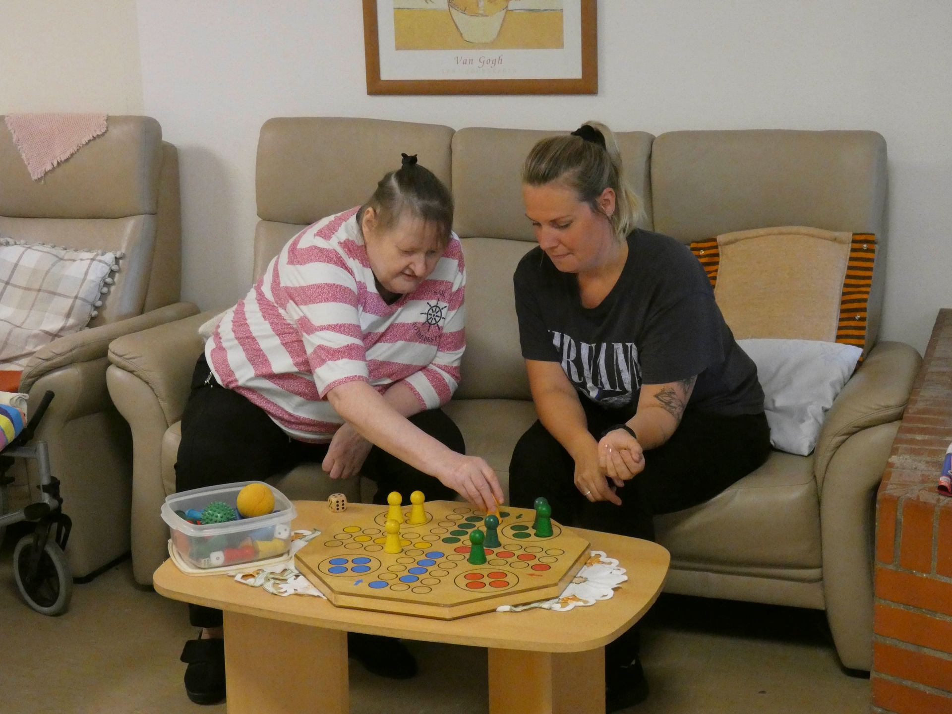 Zwei Frauen sitzen auf einer Couch und spielen ein Brettspiel.