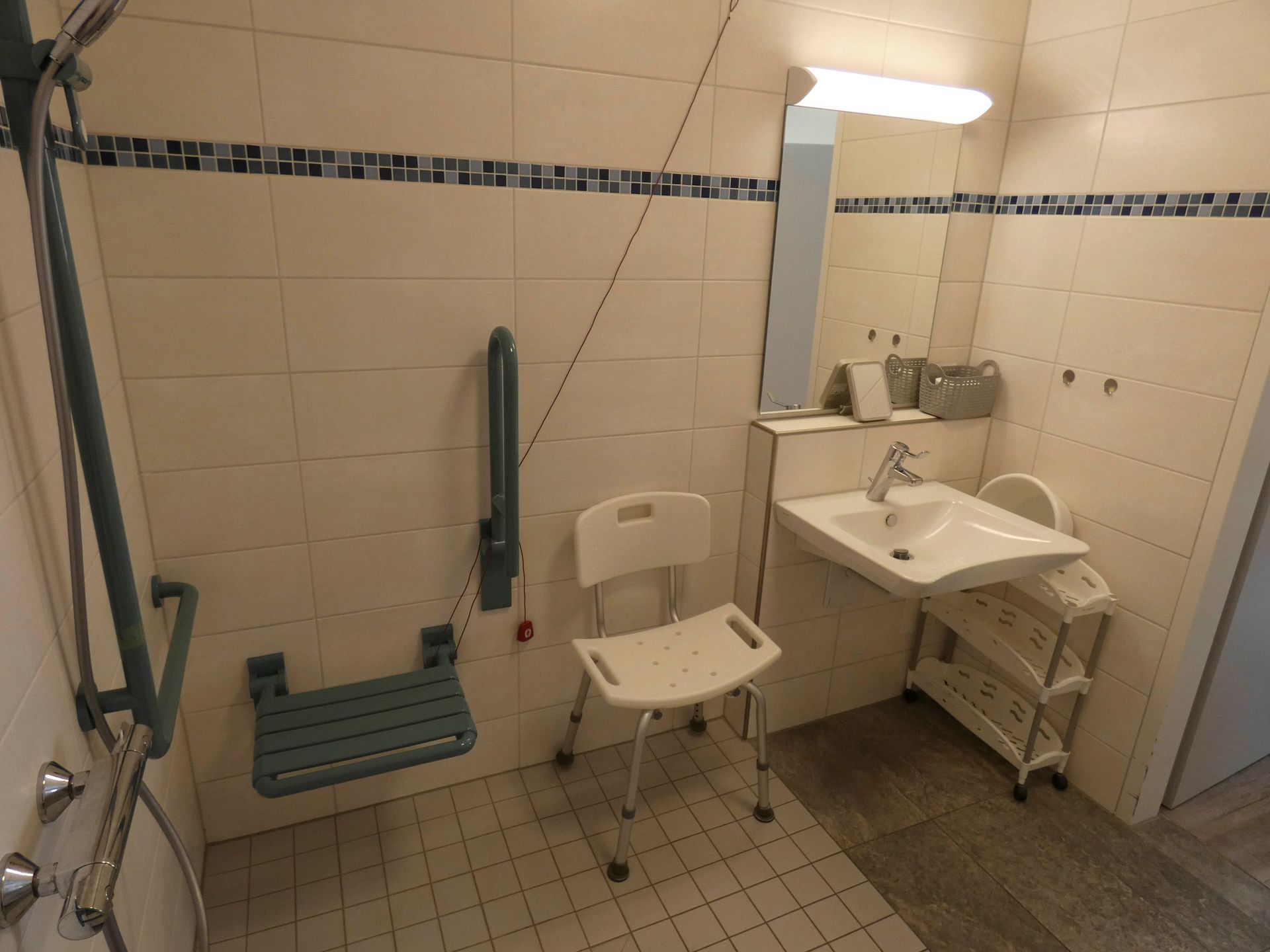 Ein Badezimmer mit Waschbecken, Stuhl, Dusche und Spiegel.