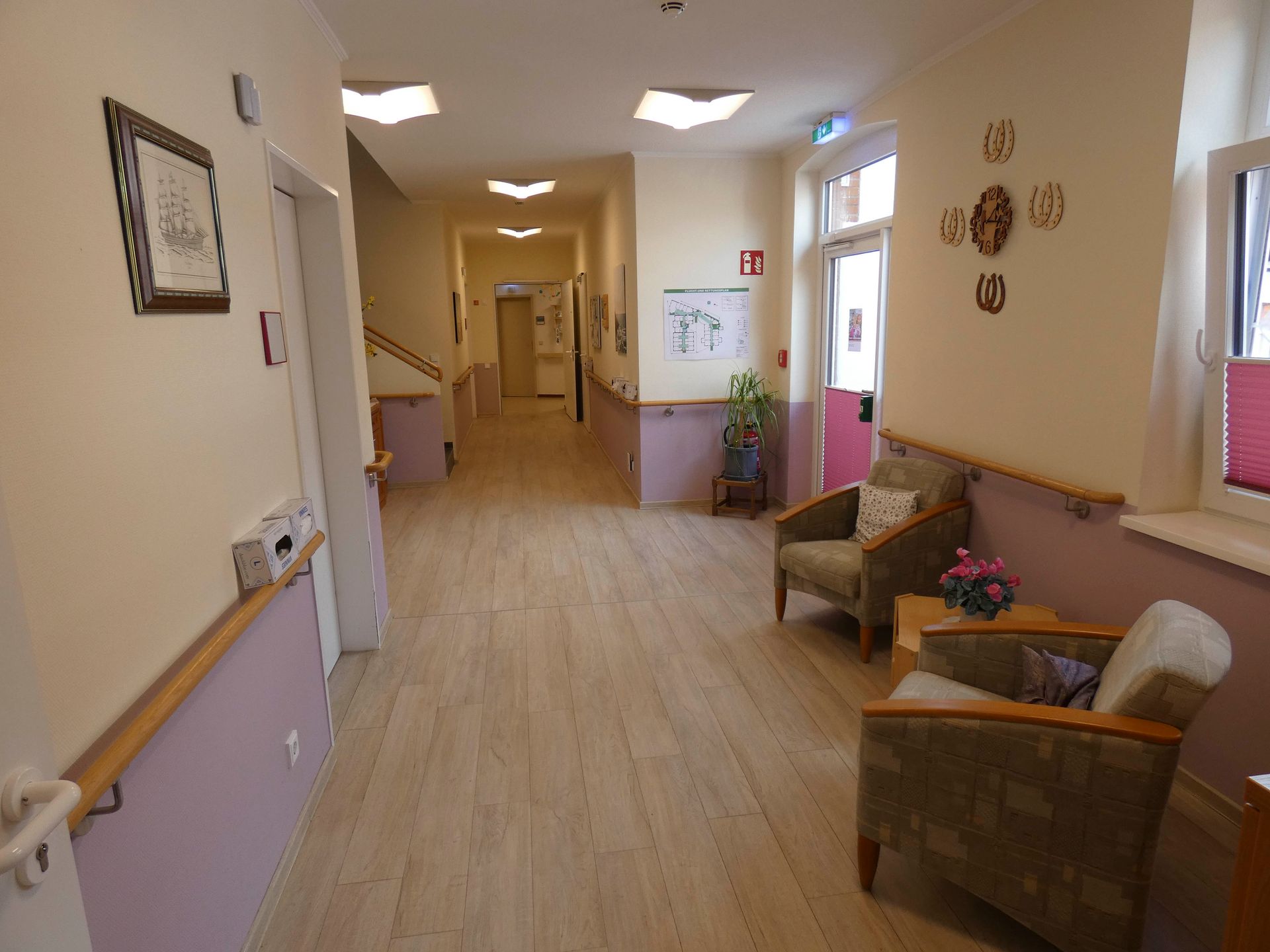 Ein langer Flur mit Stühlen und einer Uhr an der Wand.