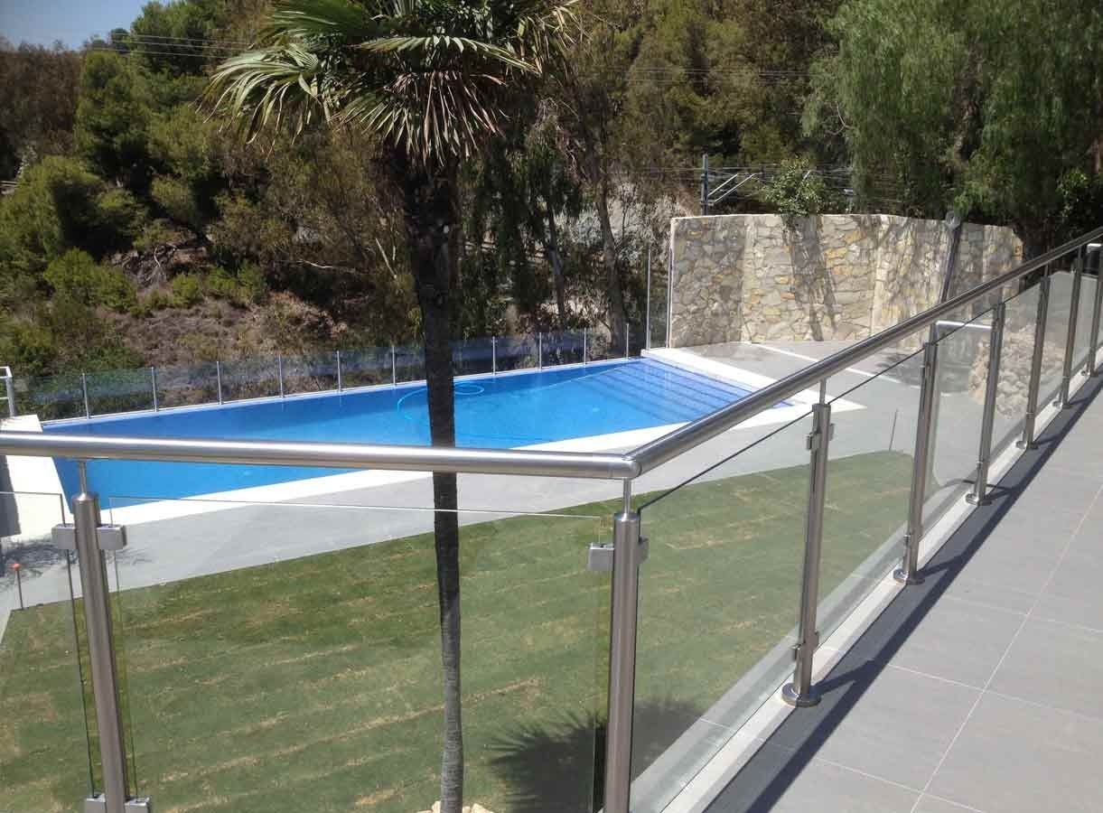 Detrás de una barandilla de cristal hay una piscina.