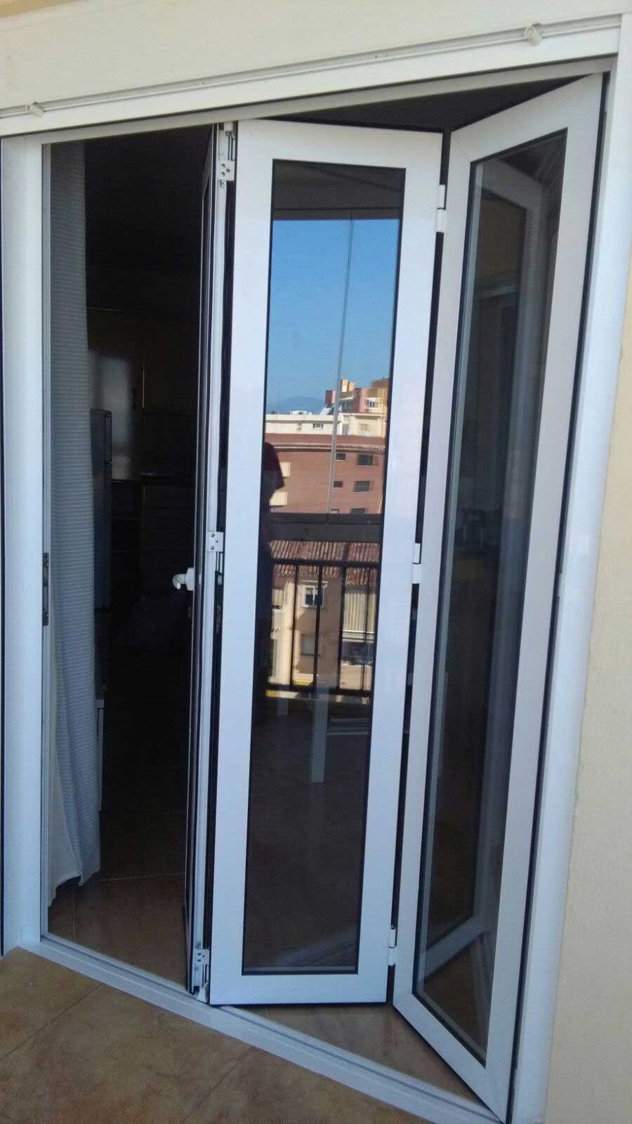 Una puerta plegable blanca se abre a un balcón.