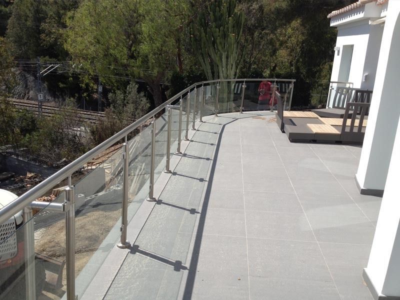 Un balcón con barandilla de acero inoxidable y suelo de baldosas.