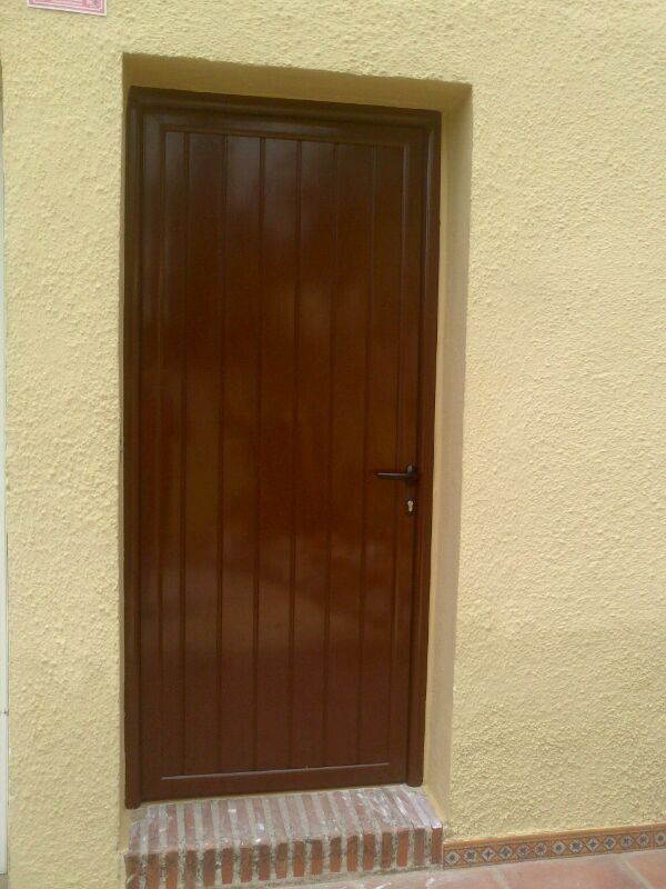 Una puerta marrón está en una pared amarilla.