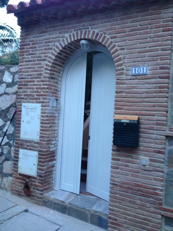 Un edificio de ladrillo con una puerta blanca y un buzón.
