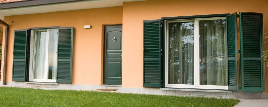 Una casa con persianas verdes en las ventanas y puertas