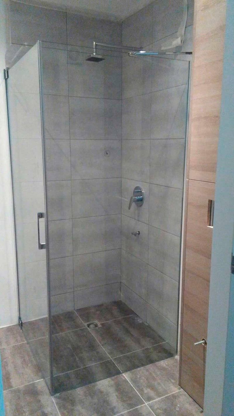 Un baño con ducha a ras de suelo y puerta de cristal.