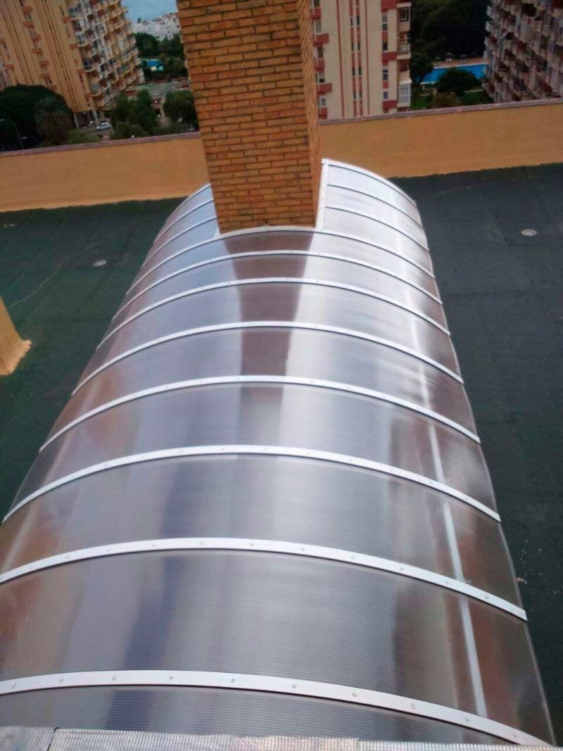 Un dosel transparente se encuentra encima de un tejado al lado de una chimenea.