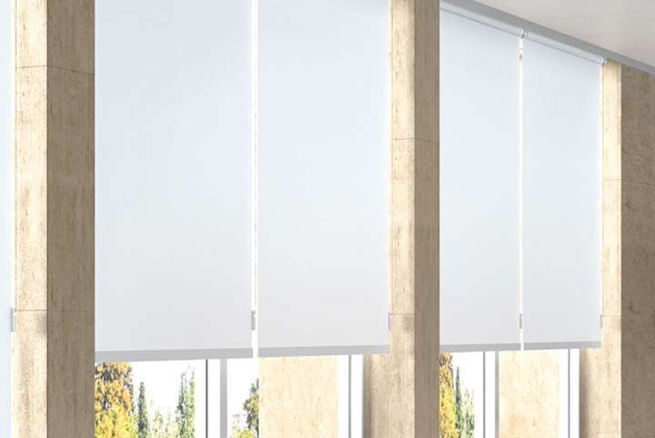 Una habitación con muchas ventanas y persianas blancas.