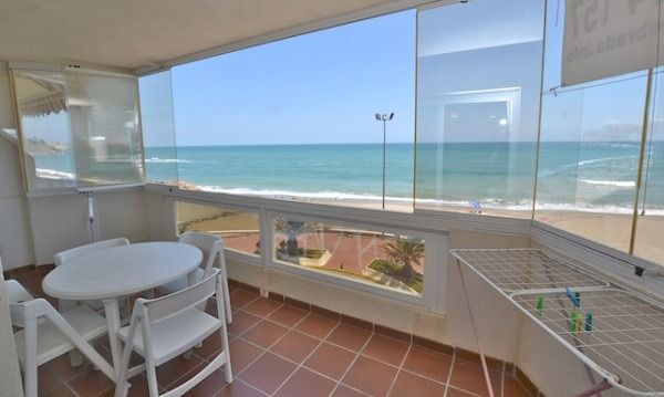Un balcón con mesa y sillas con vista al mar.