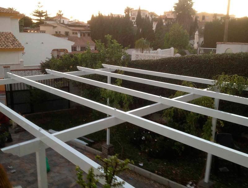 Se está construyendo una pérgola blanca en un patio trasero.