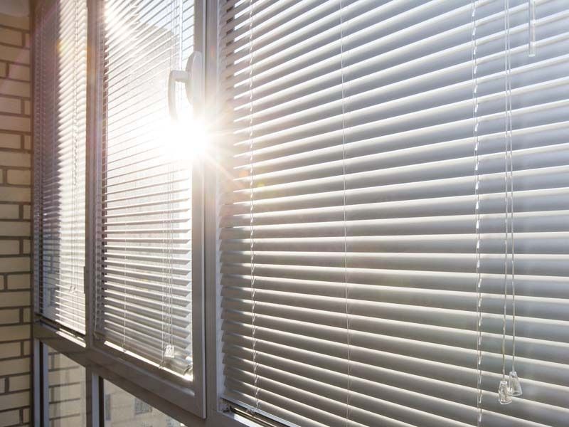 El sol brilla a través de las persianas de la ventana.