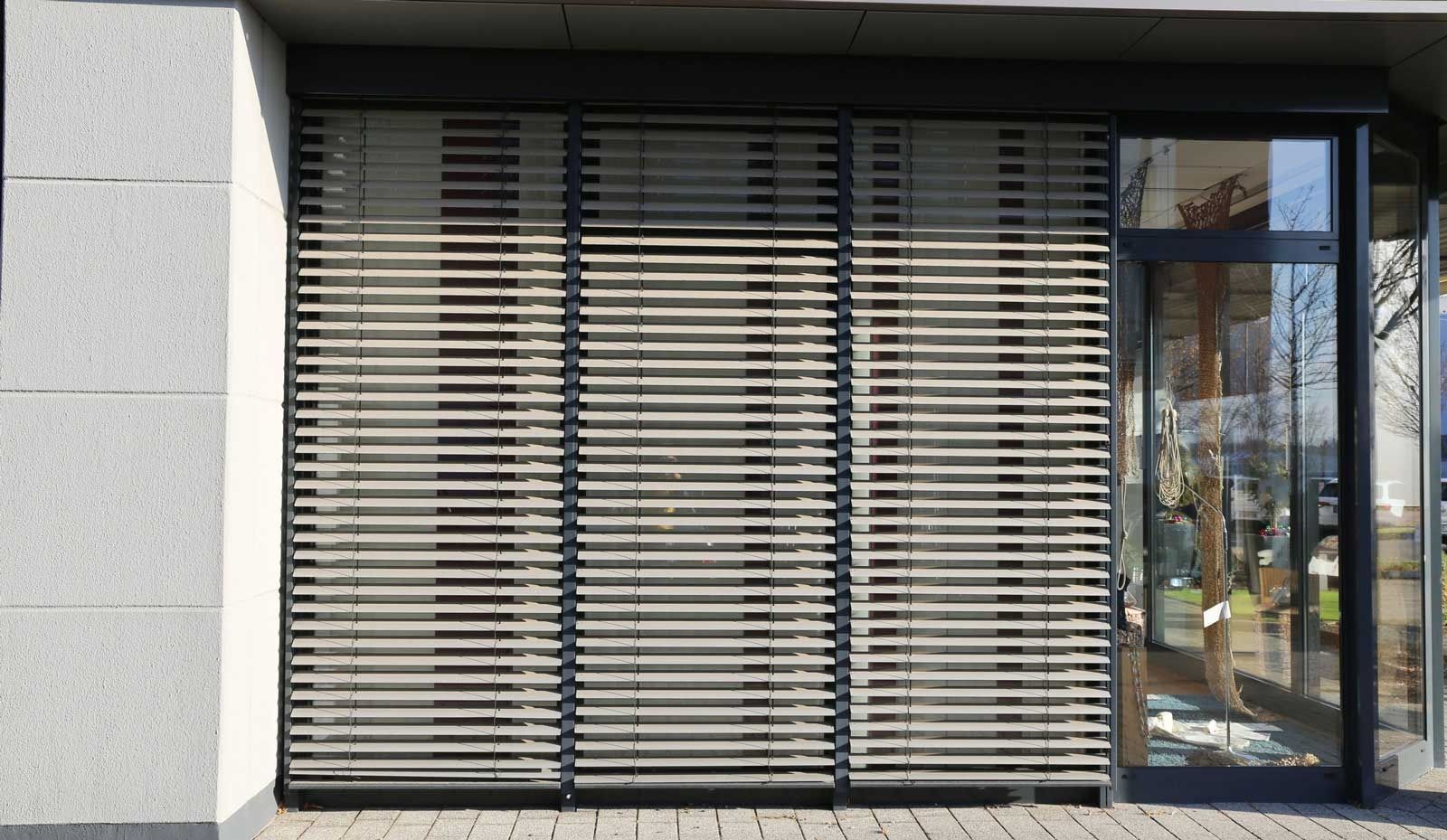 Un edificio con una puerta de vidrio y persianas en las ventanas.