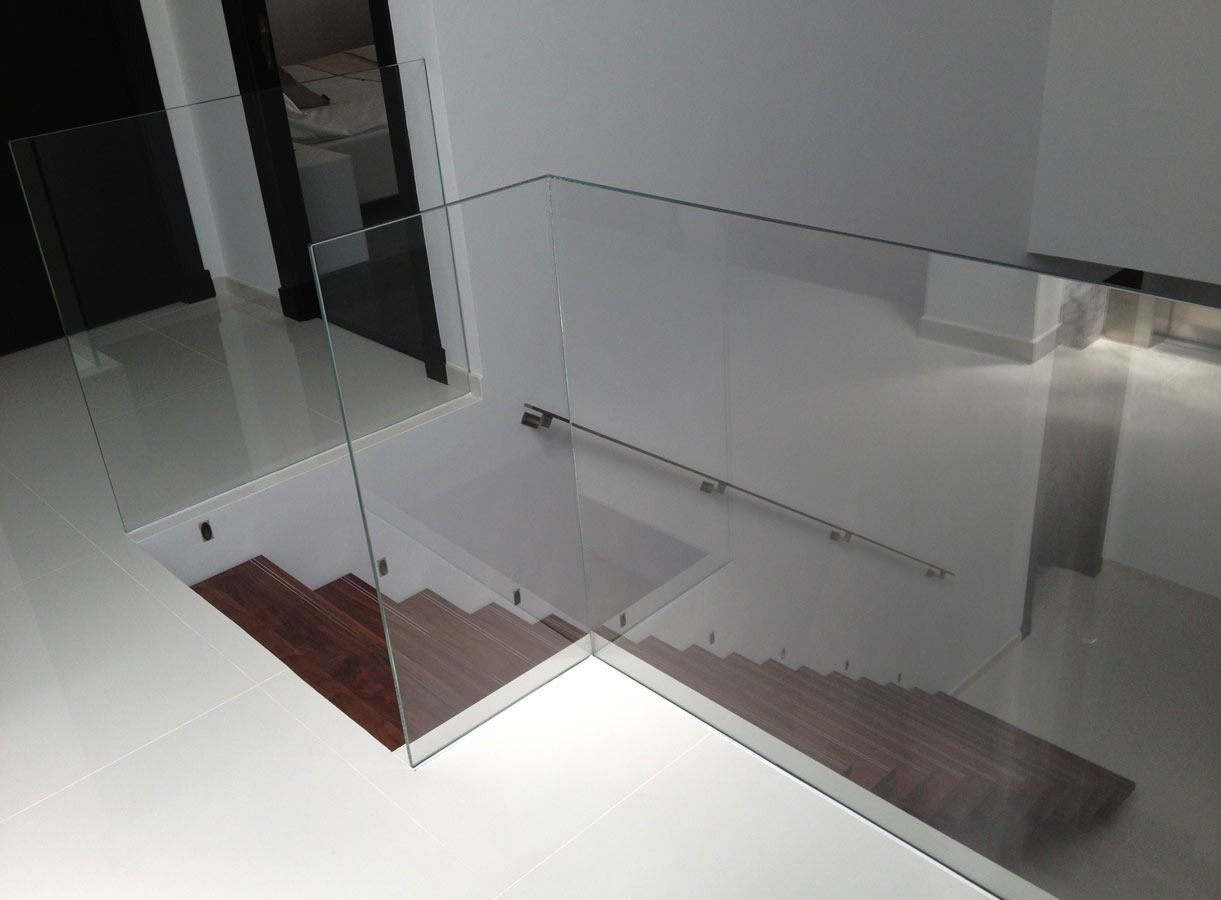 Una escalera con barandilla de cristal y escalones de madera.