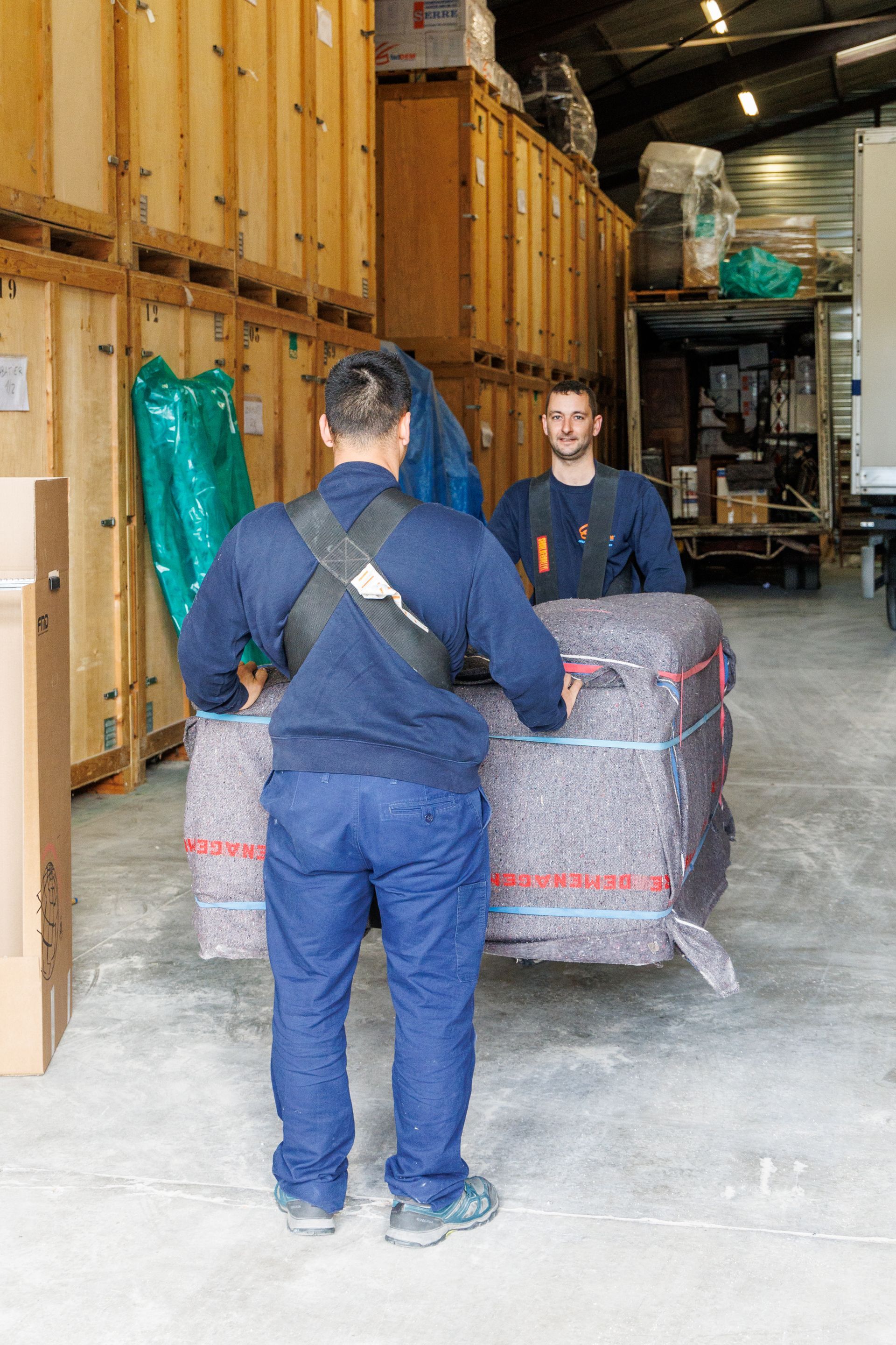 Deux professionnels de Déménagements Serre qui transportent un meuble dans leur entrepôt