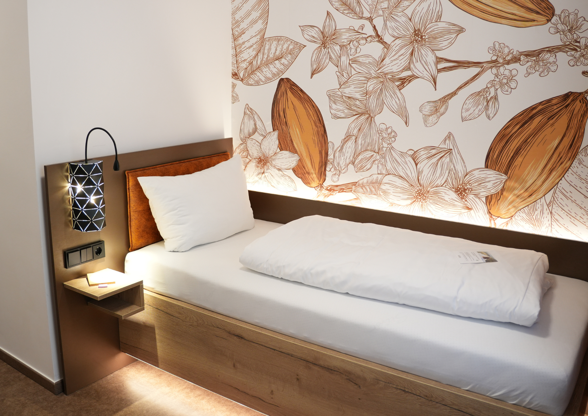 ein Hotelzimmer Einzelbett vor einer Kakaotapete