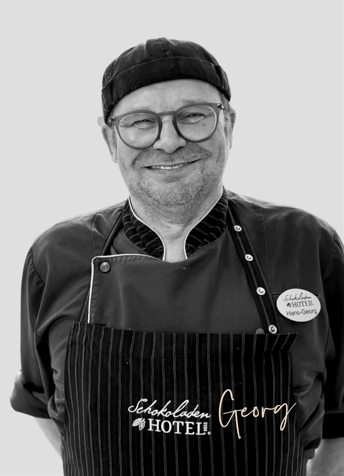 Hans-Georg, unser Küchenchef mit einem breiten Lächeln auf einem schwarz-weißes Bild.