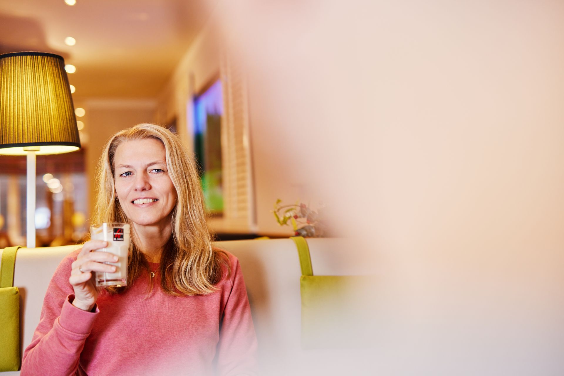 Eine Frau sitzt auf einem Stuhl und hält ein Getränk in der Hand.