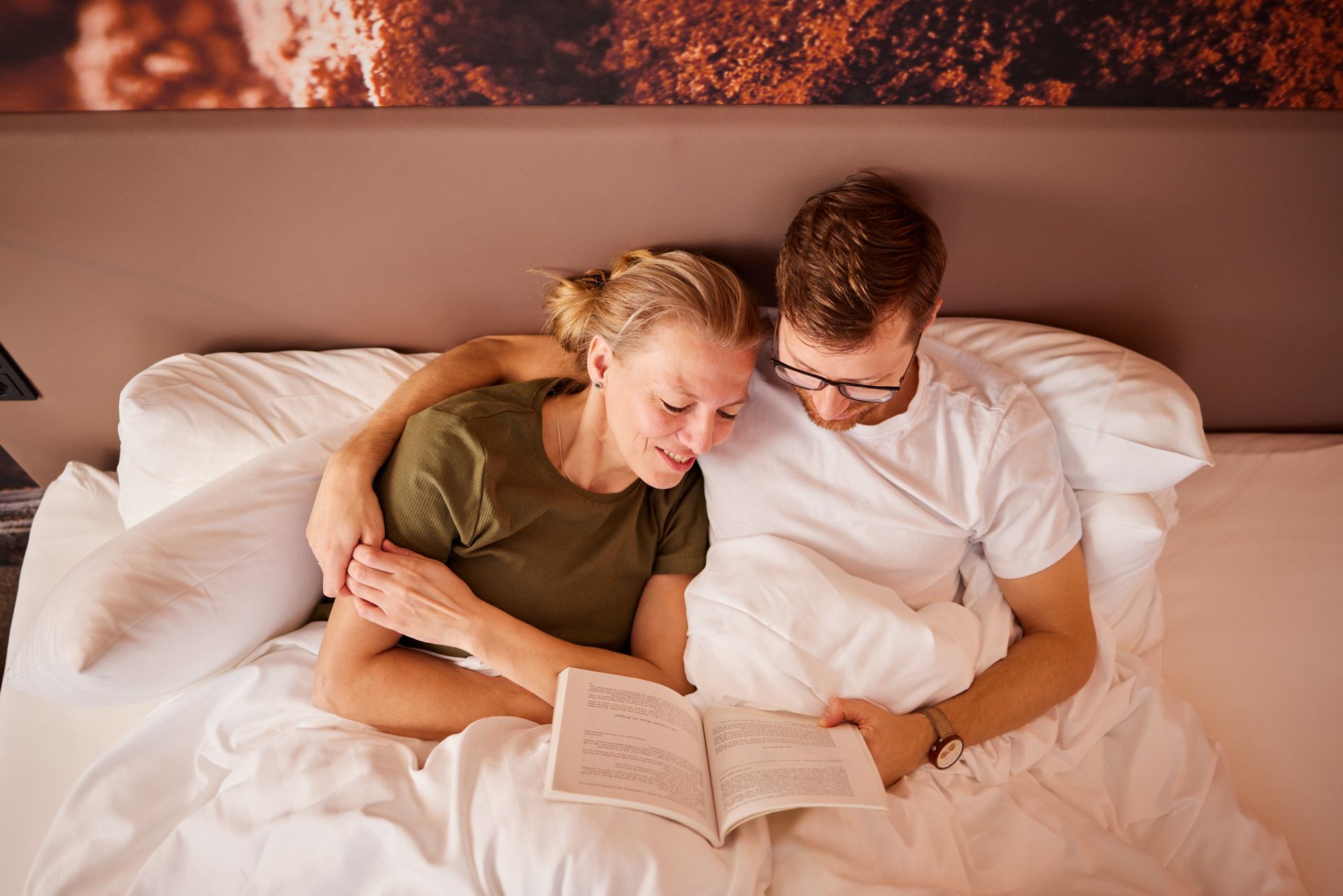 Ein Mann und eine Frau liegen im Bett und lesen ein Buch.