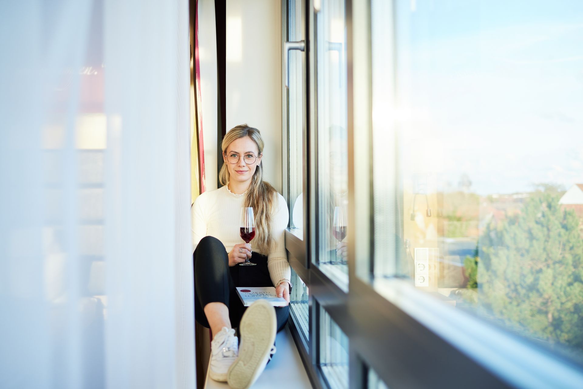 Eine Frau sitzt mit einem Glas Wein auf einem Balkon.