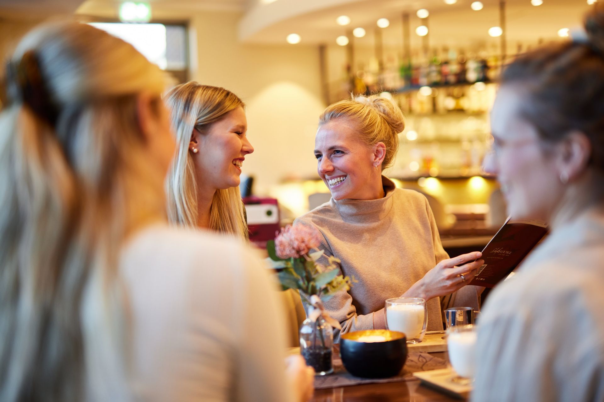 Eine Gruppe von Frauen sitzt in einem Restaurant an einem Tisch und unterhält sich miteinander.