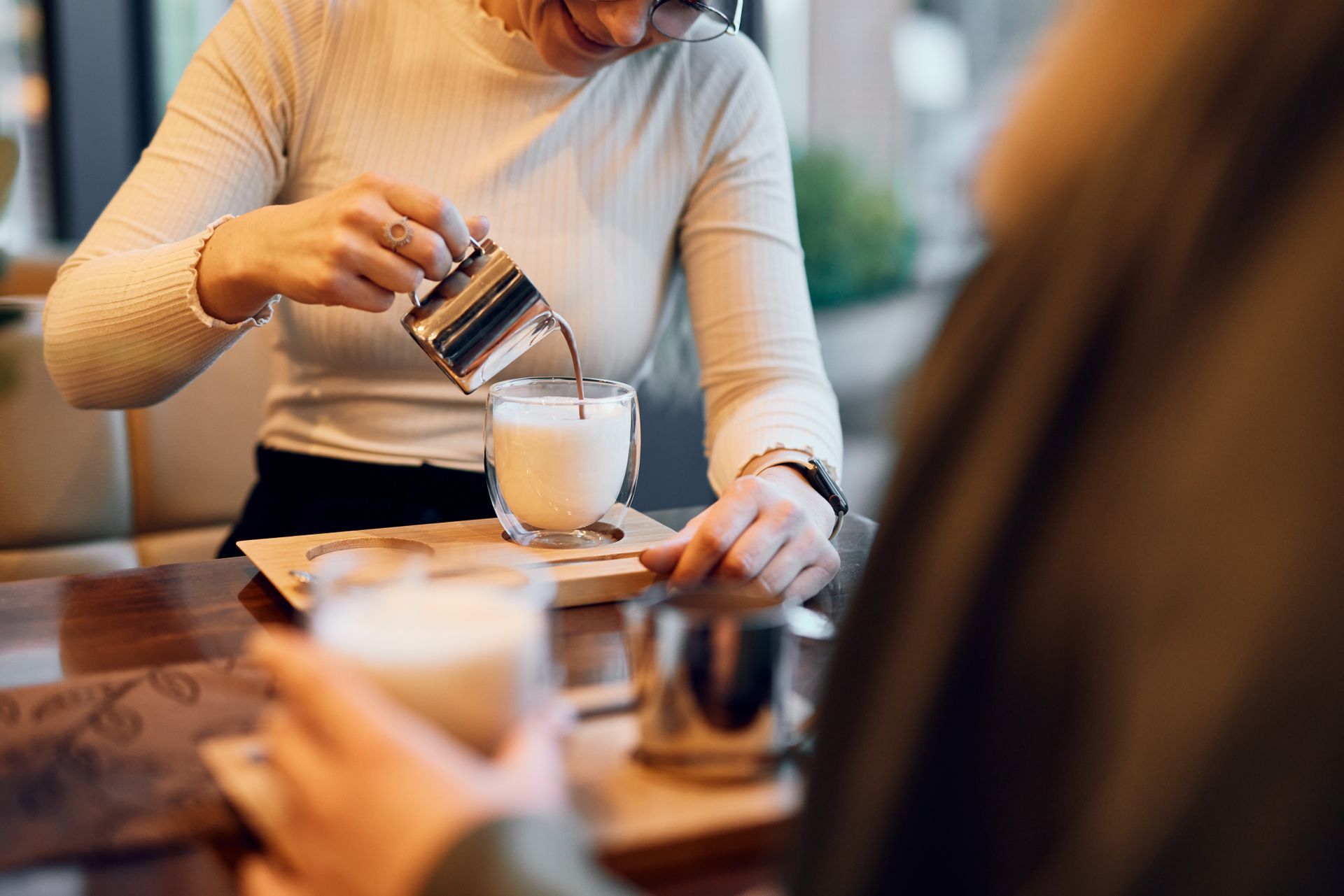 Eine Frau gießt Schokolade in ein Glas mit Milch.