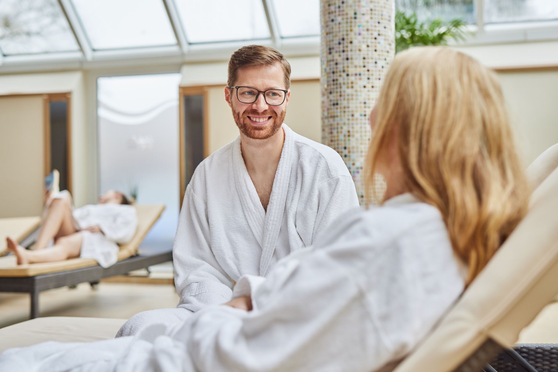 Ein Mann und eine Frau sitzen auf Liegestühlen in einem Spa.