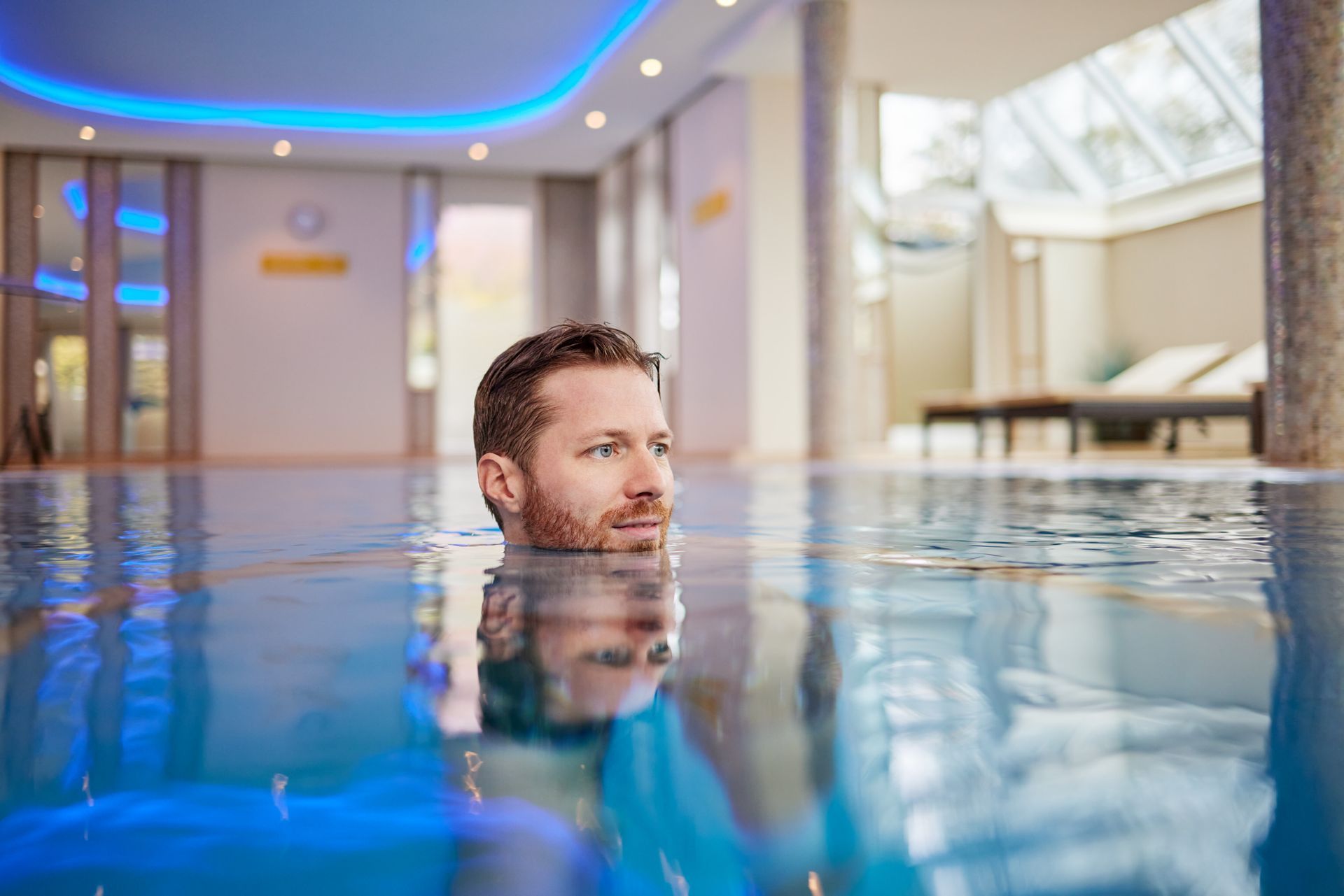 Ein Mann treibt in einem Schwimmbecken und hält dabei seinen Kopf im Wasser.