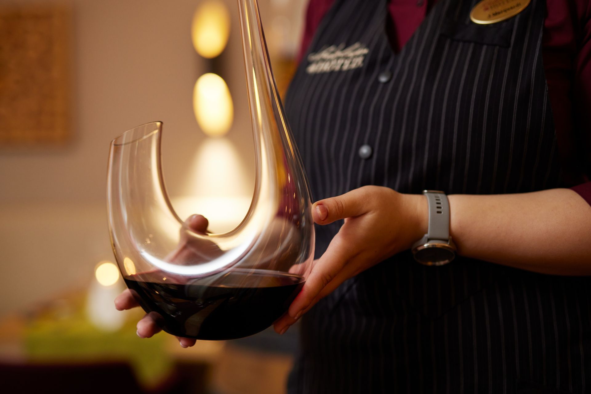 Eine Frau hält eine Karaffe und ein Glas Wein.